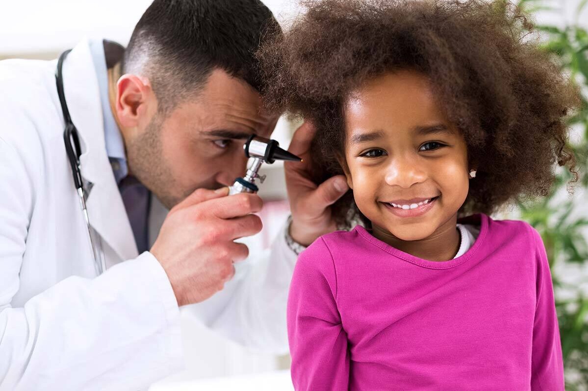 Medical practitioner examining young girl's ear