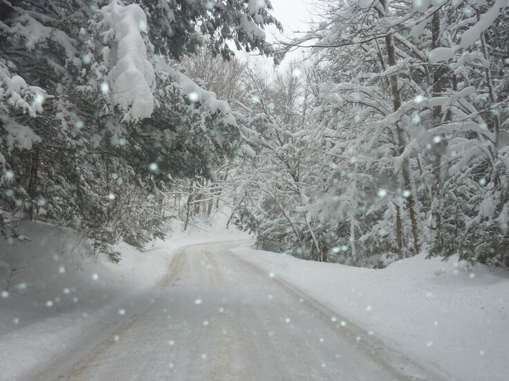 photo of a very snowy road as snow comes down