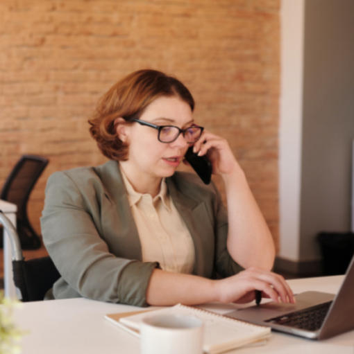 woman answering phone using laptop